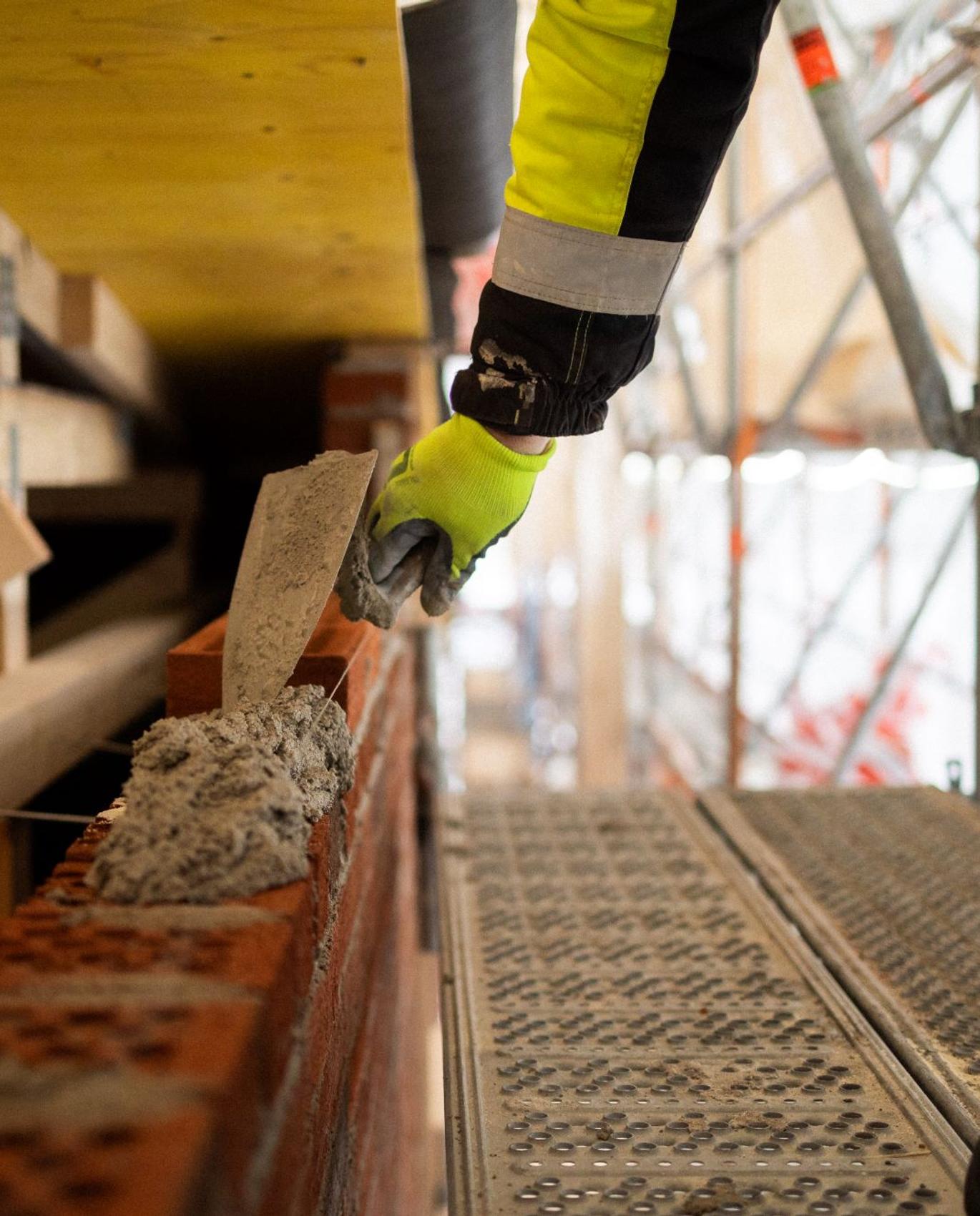 Vuokramuurari muuraamassa talon sein&auml;&auml;.